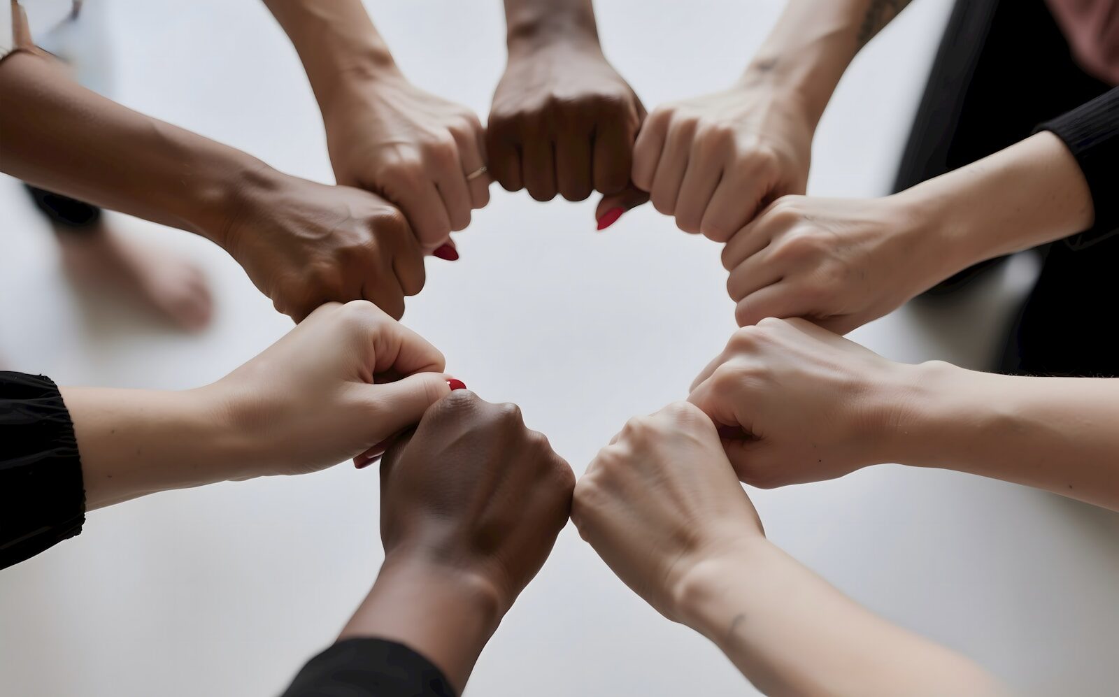 Photo by Kamil Kalkan People of diverse skin tones fist bumping in a circle.