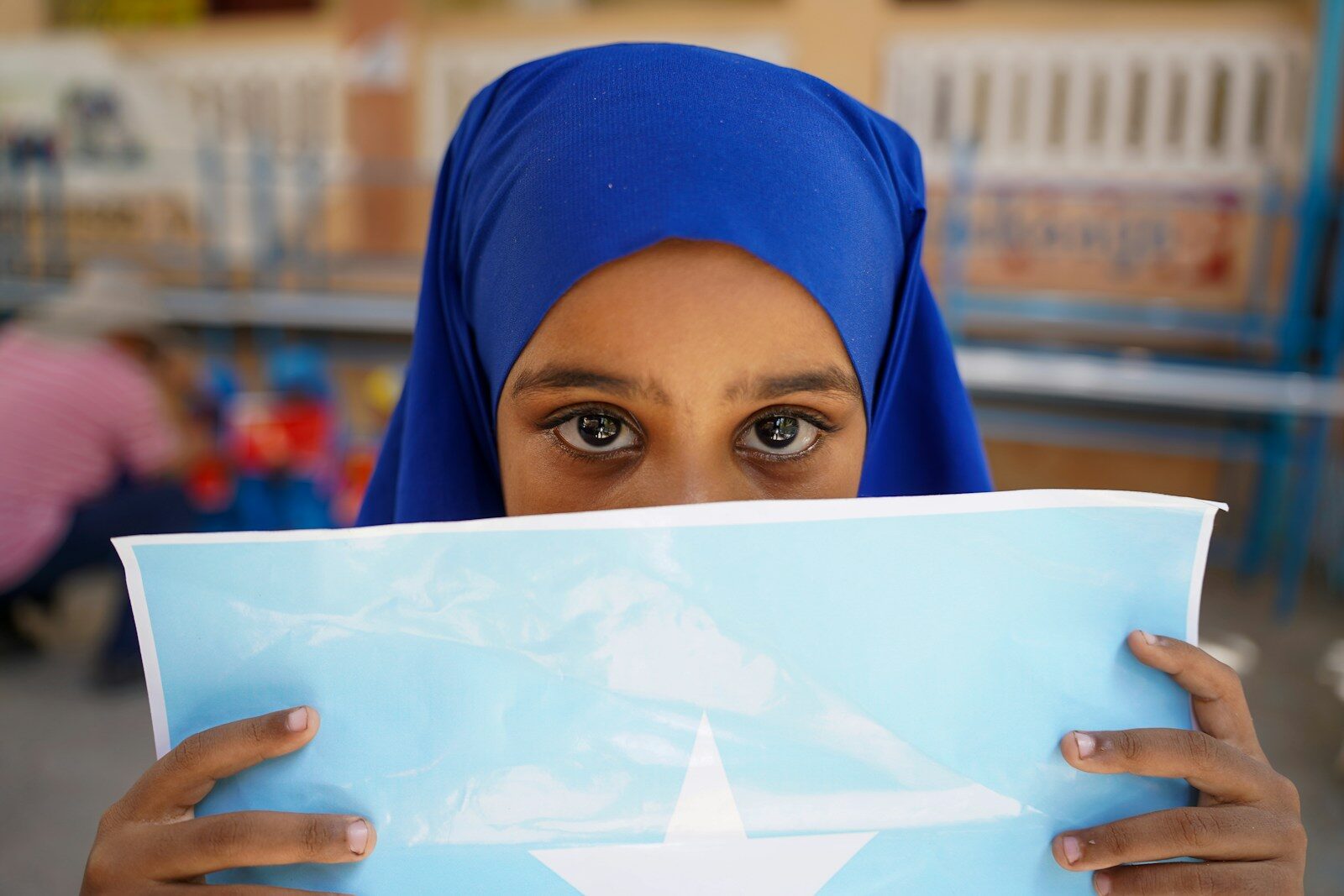 Photo by MOHAMED ABUKAR Young girl in blue hijab holds somali flag