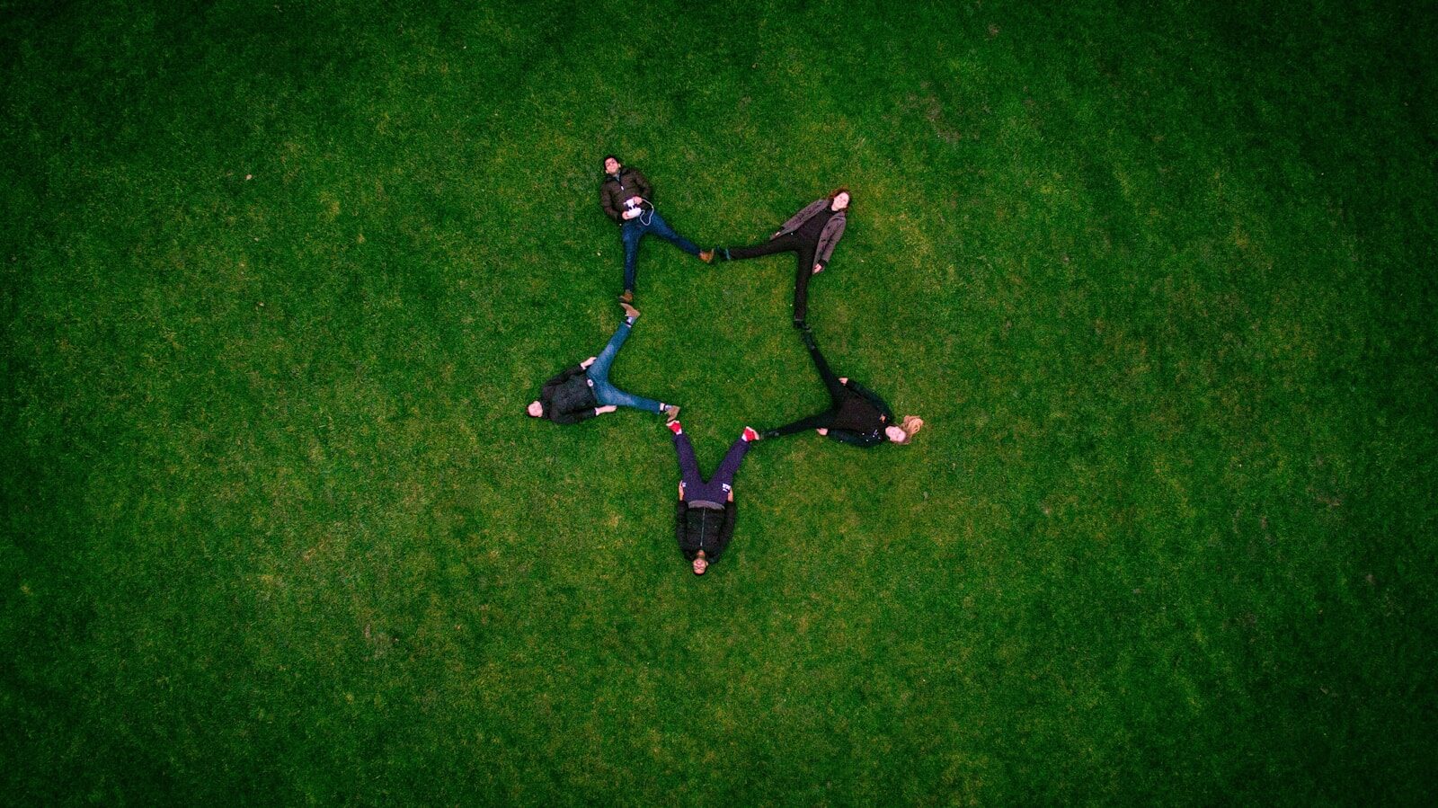 Photo by Sidharth Bhatia five people laying on grass field making star sign